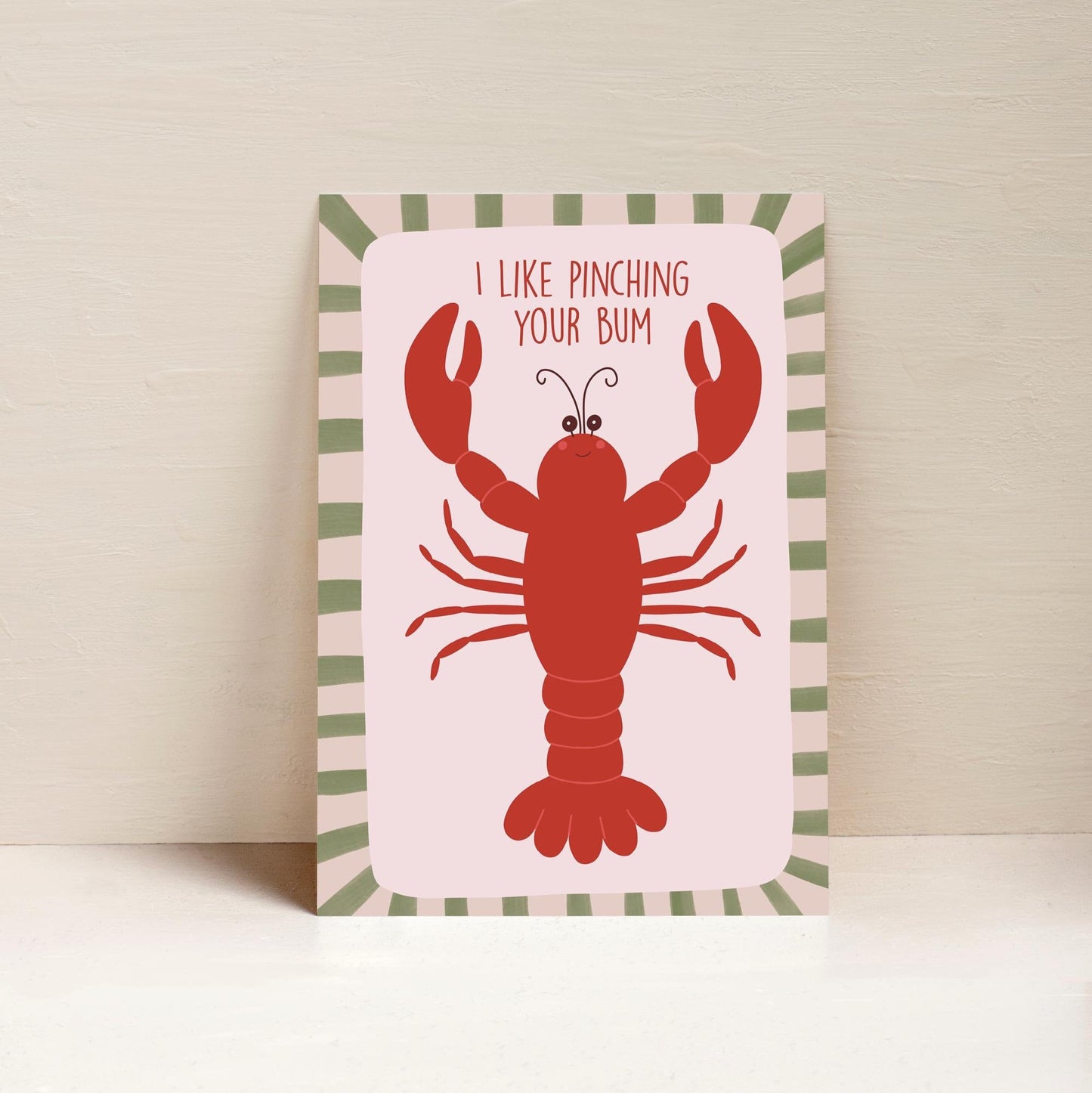 A4 art print with an illustration of a red lobster on a pink background with a striped border. The text on the print reads 'I like pinching your bum.